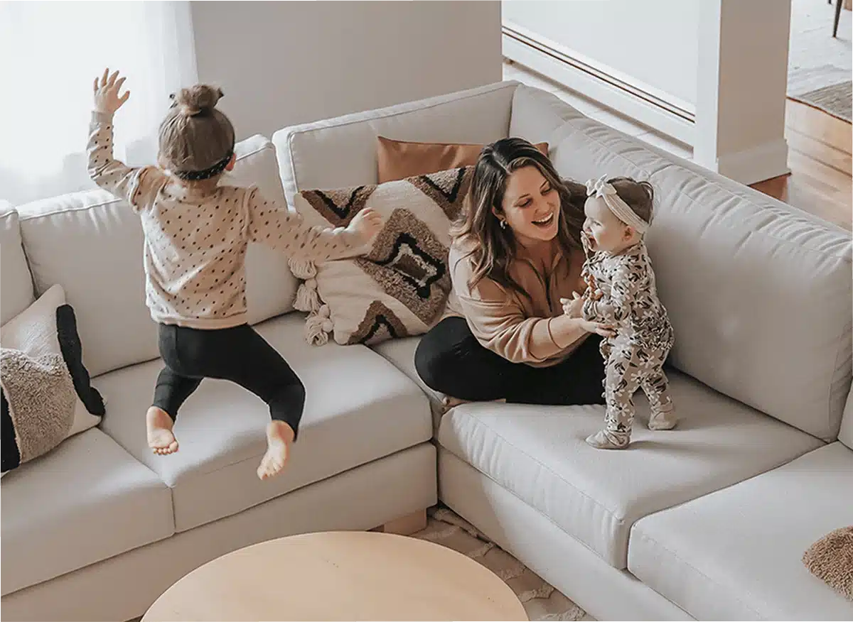 Glückliche Familie auf sauberem Sofa nach der Fleckenentfernung – gemütliches Wohnzimmer 2026